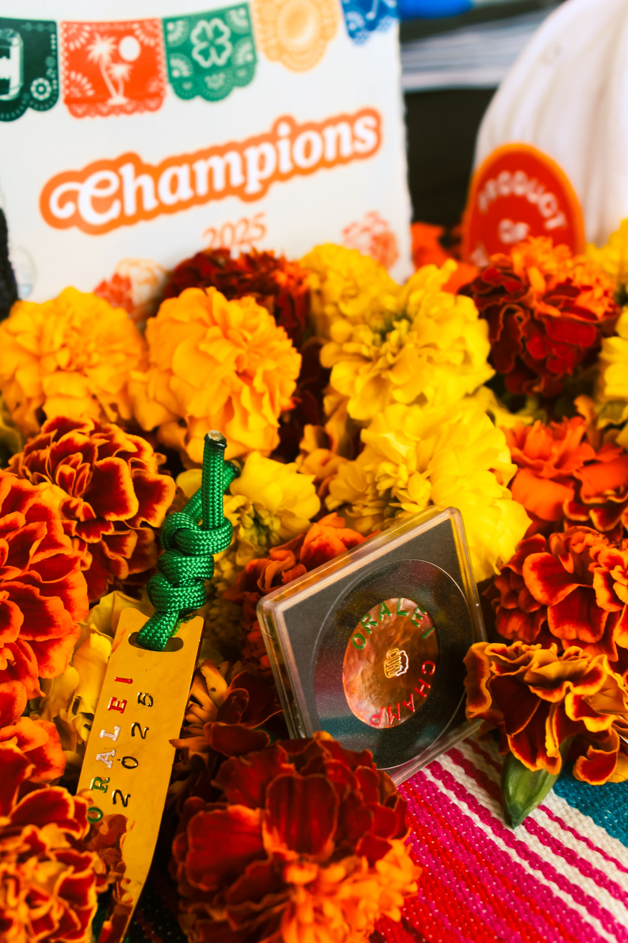 Órale awards — brass bag tag, challenge coin, cap and Champions 2025 sign